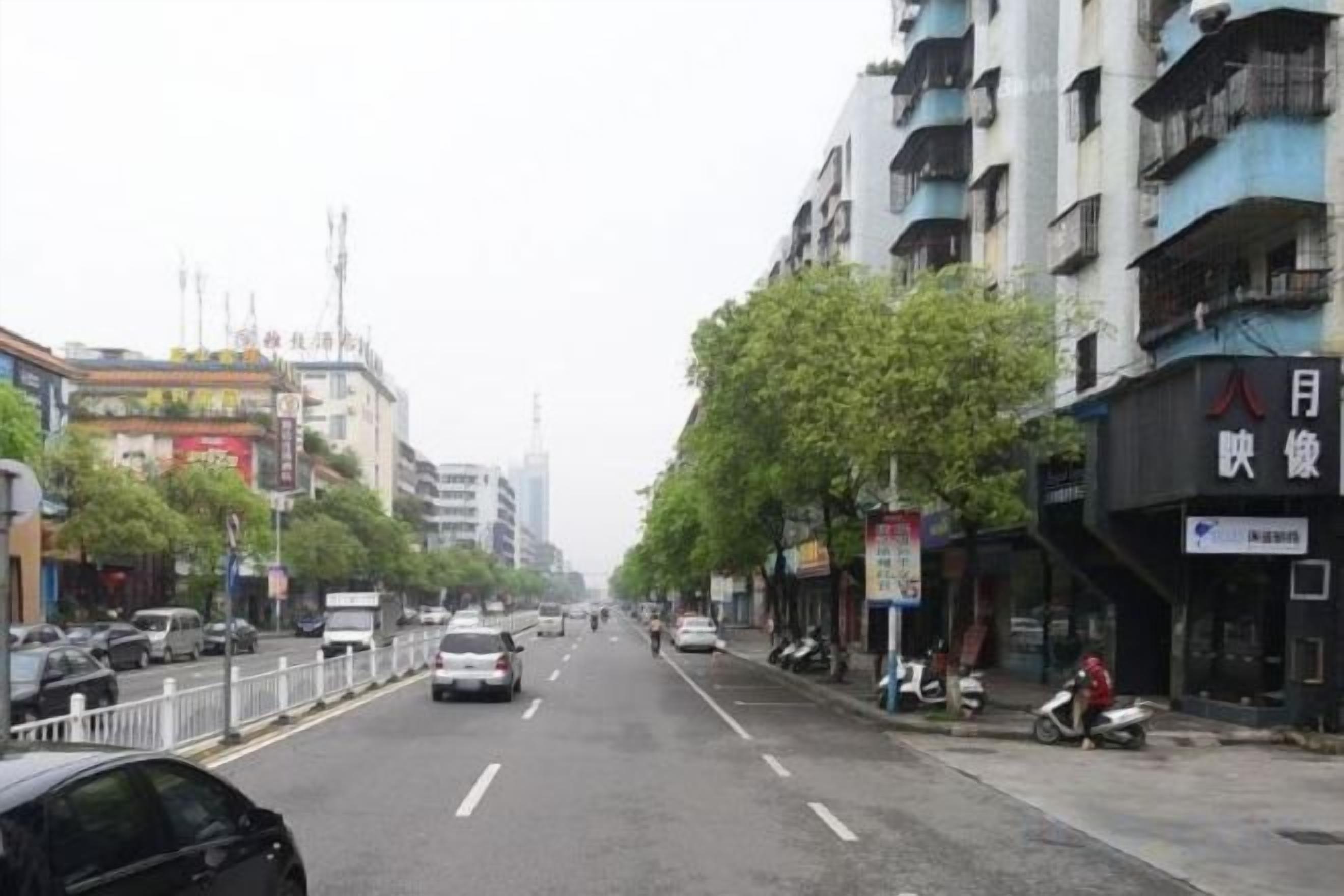 Una calle con edificios, coches y algunos peatones.