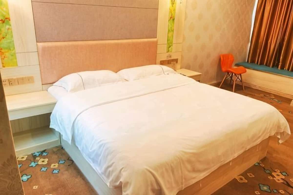 A neatly made bed with white linens, a wooden headboard, and a small orange chair.