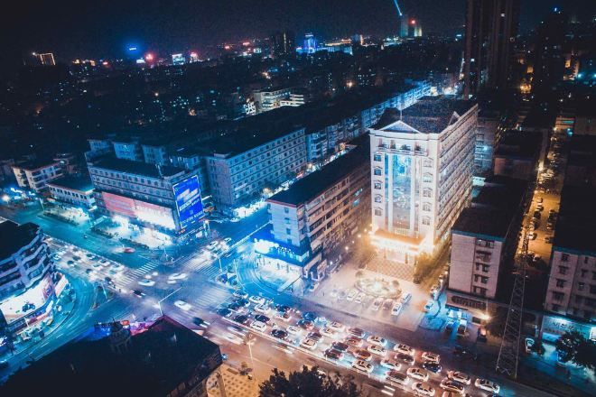 Un paisaje urbano nocturno con edificios iluminados y calles concurridas.