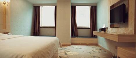 Una habitación de hotel con cama, televisión, ventana y alfombra.