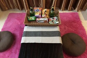 A tray of snacks and drinks on a pink rug with a striped cushion in front.
