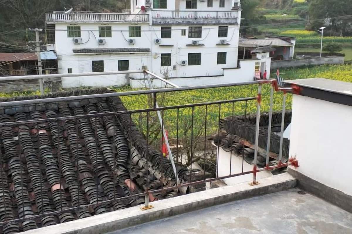 Una terraza con cerco de metal y un edificio blanco al fondo.