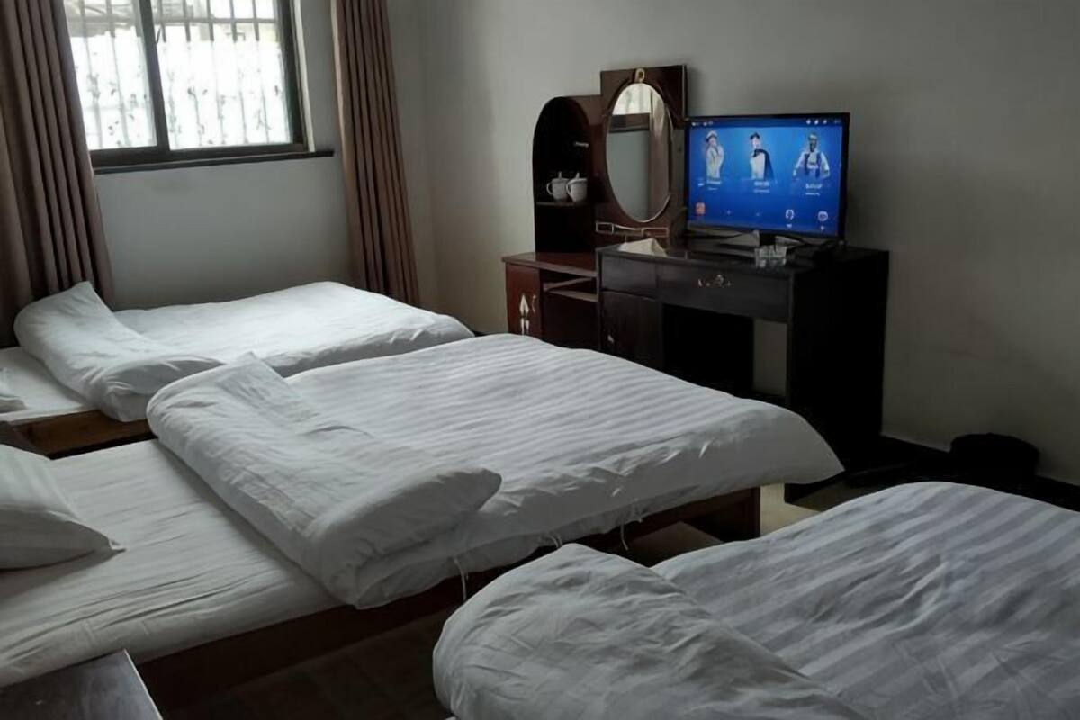 Habitación de hotel con dos camas, un escritorio con computadora, un espejo y una ventana con cortinas.