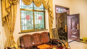 A traditional room with a wooden sofa, a table with a teapot, and a door with decorative metalwork. - Xifengkezhan (Wuyuan)