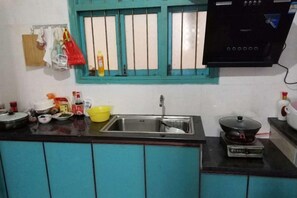 A kitchen with a sink, stove, and window with curtains. - Xifengkezhan (Wuyuan)