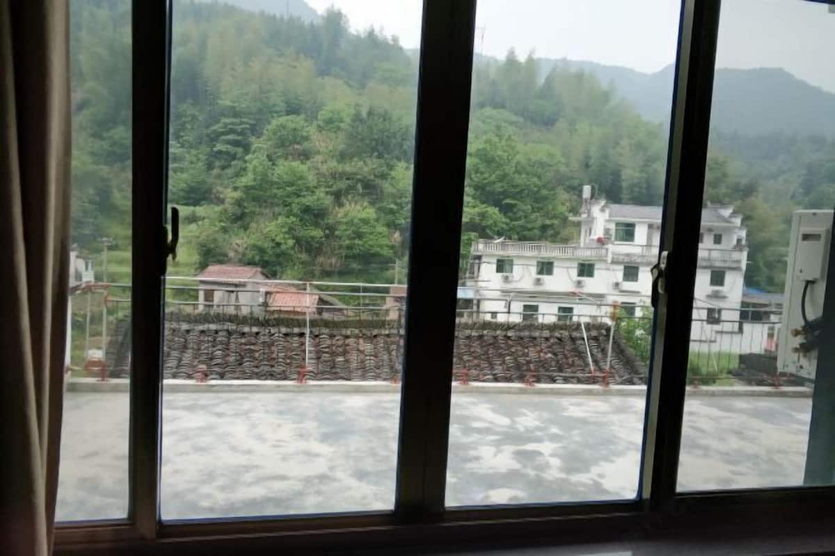 Vista desde una ventana de un edificio, mostrando una obra en construcción y una ladera cubierta de bosque.