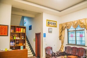 A room with a staircase, a wooden bookshelf, a sofa, and a window with curtains. - Xifengkezhan (Wuyuan)