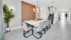 Ein moderner Essbereich mit einem weißen Tisch, grauen Stühlen und einer Wand mit Holzvertäfelung.