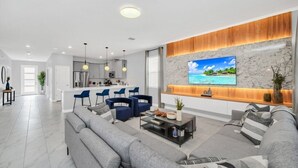 Ein modernes Wohnzimmer mit einer großen Couch, einem Couchtisch und einem an einer Marmorwand befestigten Fernseher.