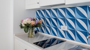 Eine Küche mit weißen Schränken, einer blau-weißen Spritzschutzverkleidung und einer Blumenvase auf der Arbeitsplatte.