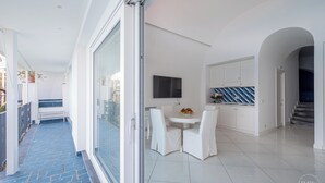 Eine moderne Küche mit weißen Schränken, einem Flachbildfernseher und einem Essbereich mit weißen Stühlen und einem Tisch.