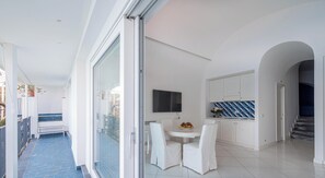 Une cuisine moderne dotée d’un téléviseur à écran plat, de meubles blancs et d’un dosseret de crédence recouvert de carreaux bleus.