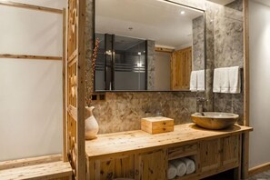 Un tocador de madera con salpicadero de mármol, un espejo grande y un mueble de madera debajo.