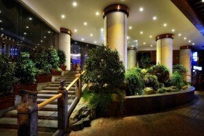 A hotel lobby with a central staircase, columns, and potted plants. - City Cottage Hotel (Chengdu Luomashi Metro Station) (Chengdu)
