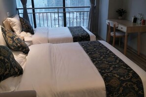 A hotel room with two beds, a desk, and a view of a cityscape. - City Cottage Hotel (Chengdu Luomashi Metro Station) (Chengdu)