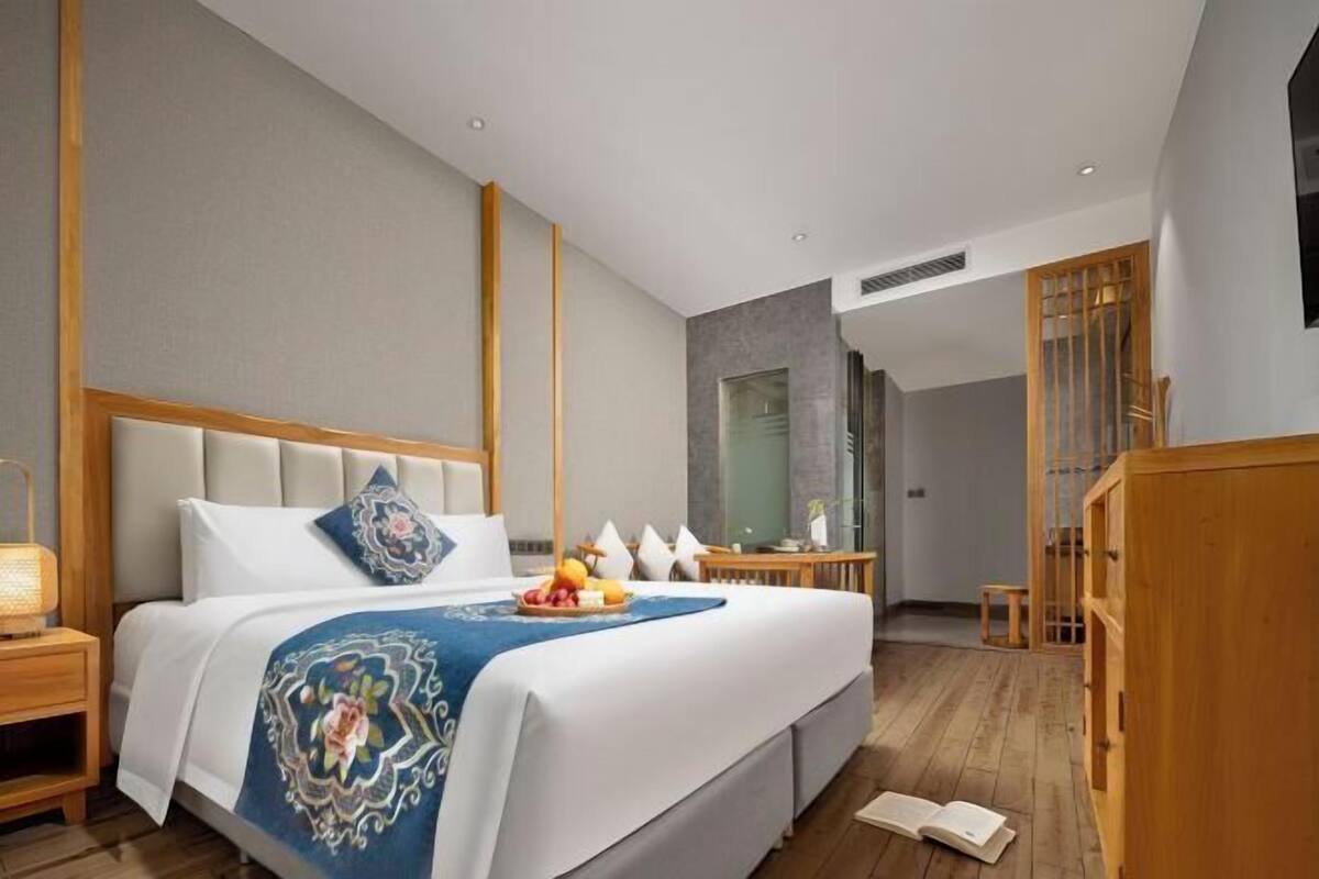 Una habitación de hotel moderna con una cama grande, una mesita de noche de madera, un escritorio y un armario.