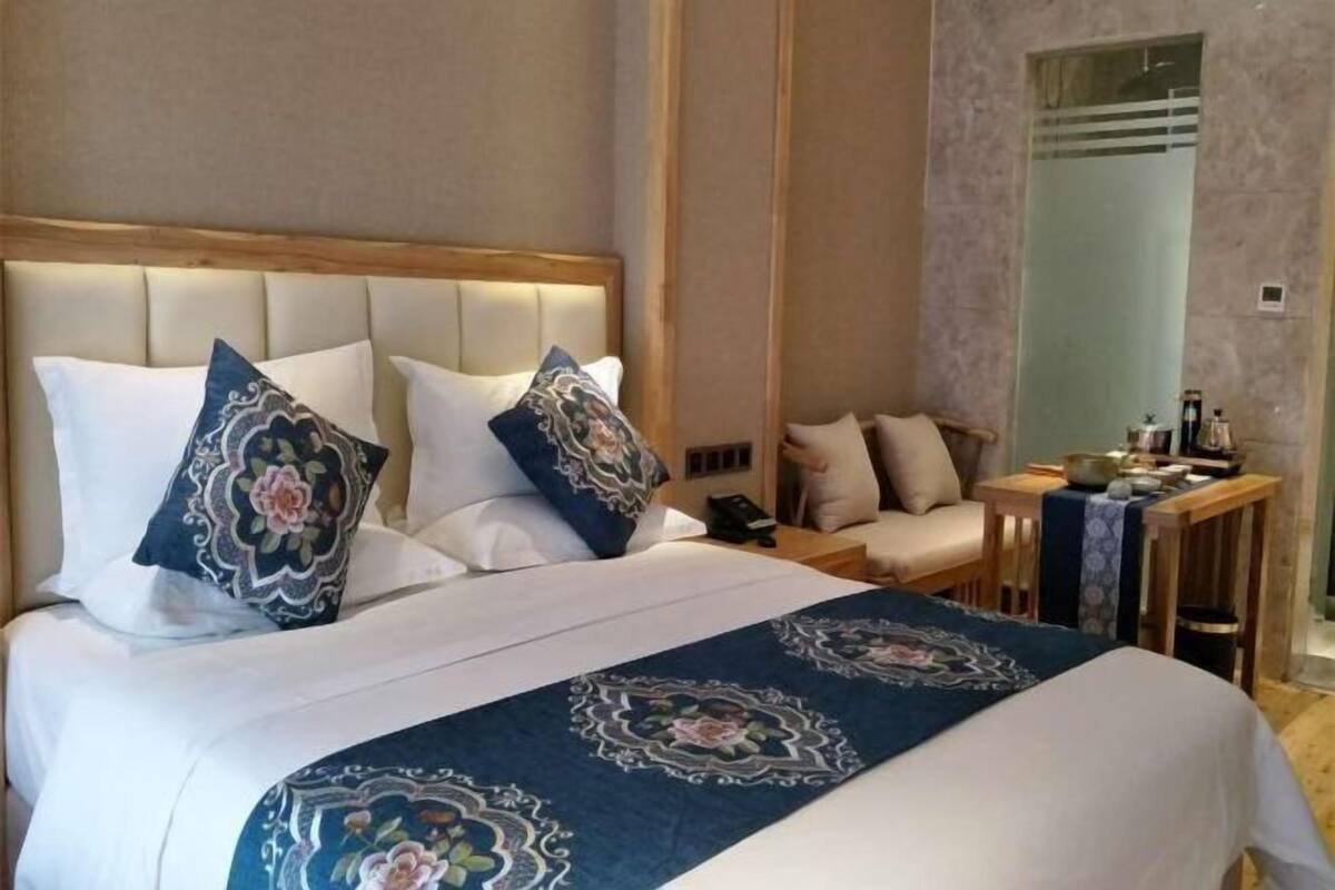 Una habitación de hotel con cama, mesita de noche, silla y espejo.
