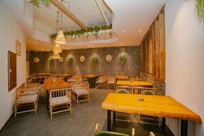 A restaurant with wooden tables and chairs, hanging plants, and a brick wall. - City Cottage Hotel (Chengdu Luomashi Metro Station) (Chengdu)