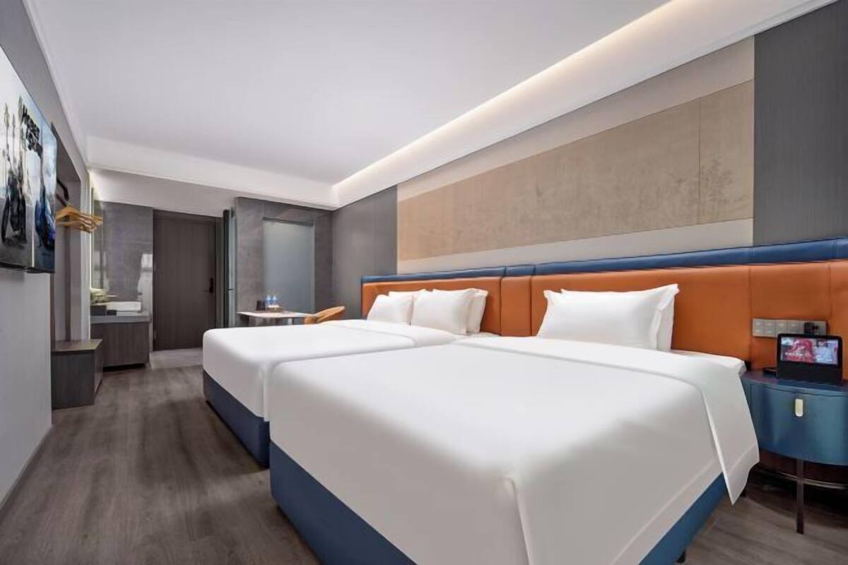 Habitación de hotel con dos camas, un escritorio, un televisor y un baño.