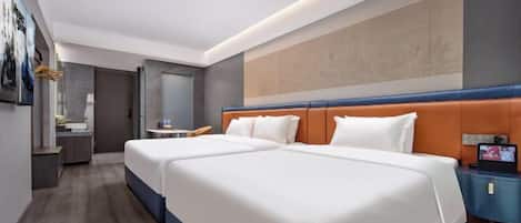 A hotel room with two beds, a desk, a TV, and a bathroom.