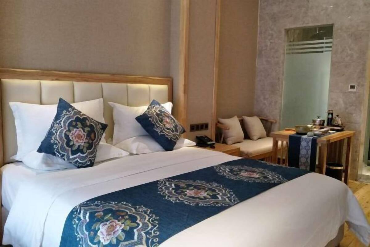 Una habitación de hotel con una cama grande, una mesita de noche, una silla y un espejo.