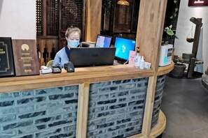 A reception desk with a computer, a phone, and a small plant. - City Cottage Hotel (Chengdu Luomashi Metro Station) (Chengdu)