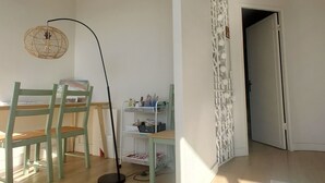 A room with a wooden floor, a green chair, a table, a floor lamp, and a door leading to another room. - South-facing, pleasant, quiet 65 ㎡ (Montpellier)