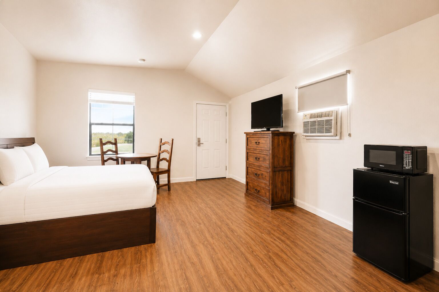 Un dormitorio con cama, cómoda de madera, televisor y refrigerador.