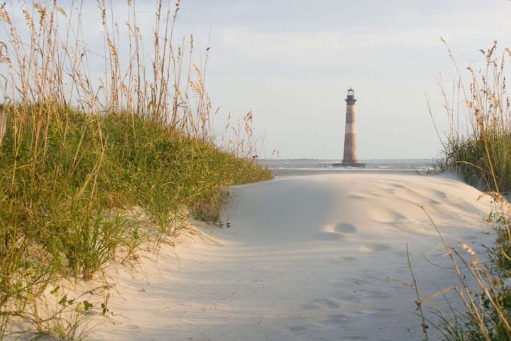 A sandy path leading to a lighthouse.