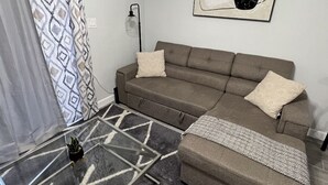 Ein Wohnzimmer mit einer Couch, einem Glastisch und einem gemusterten Teppich.