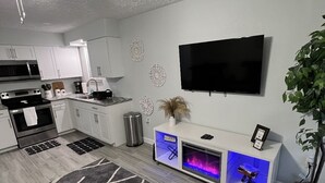 Eine moderne Küche mit weißen Schränken, einem schwarzen Fernseher und einem Kamin.