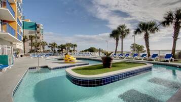 A swimming pool with blue-tiled edges, palm trees, and lounge chairs.