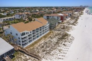 Ein Küstenhotel mit mehreren Etagen, Meerblick und einer Prominade, die zum Strand führt.