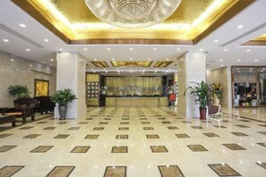 A hotel lobby with a reception desk, seating area, and decorative plants. - Jialida Hotel (Guangzhou)