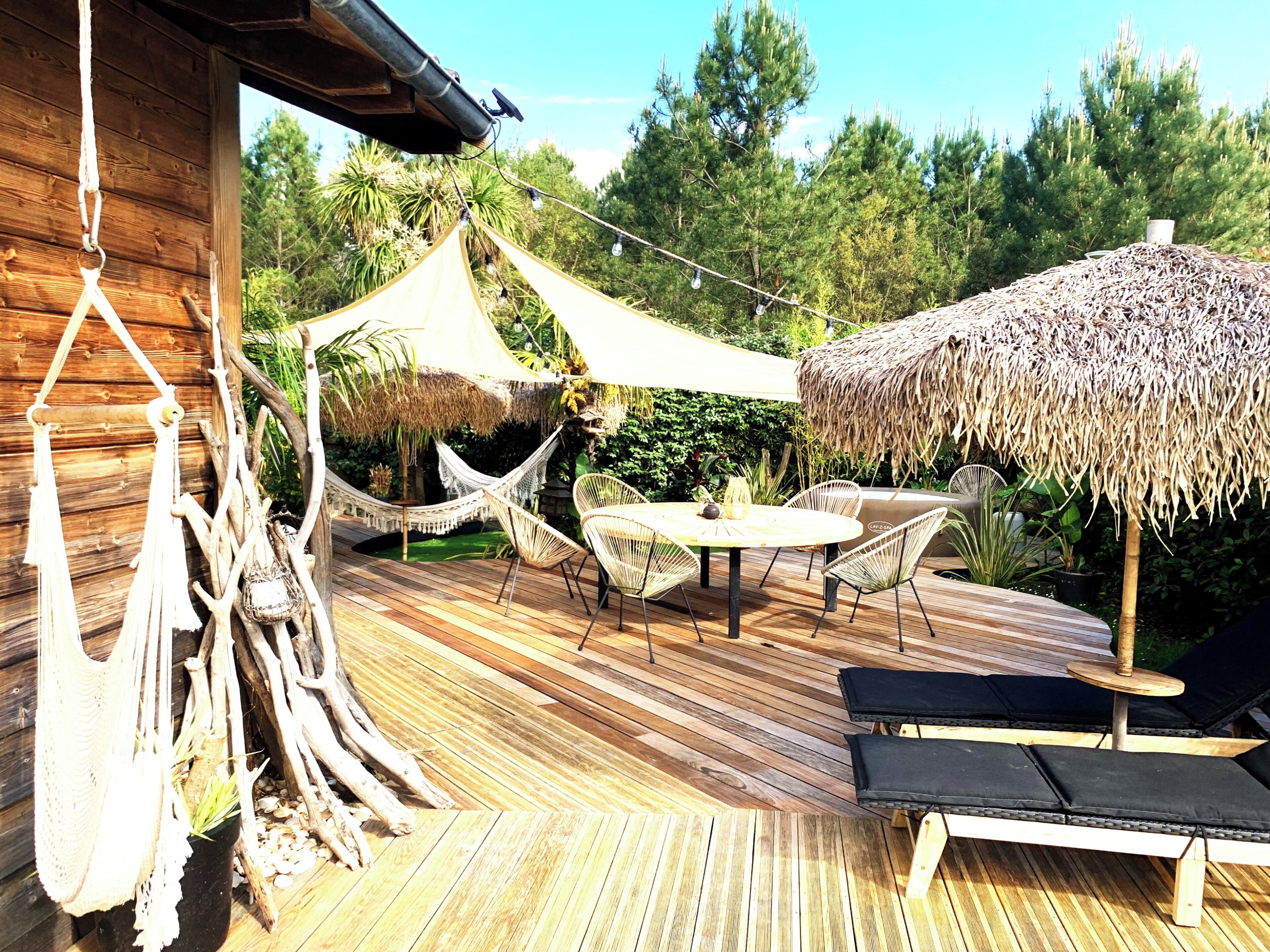 A wooden deck with a hammock, a round table, and lounge chairs.
