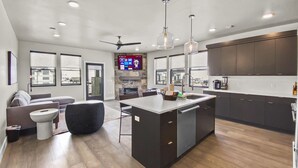 A modern kitchen with dark cabinetry, a central island, and pendant lighting.
