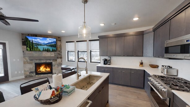 A modern kitchen with a stone fireplace, a large island, and a built-in stove.