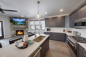 Una cocina moderna con chimenea de piedra, una isla grande y una estufa integrada.