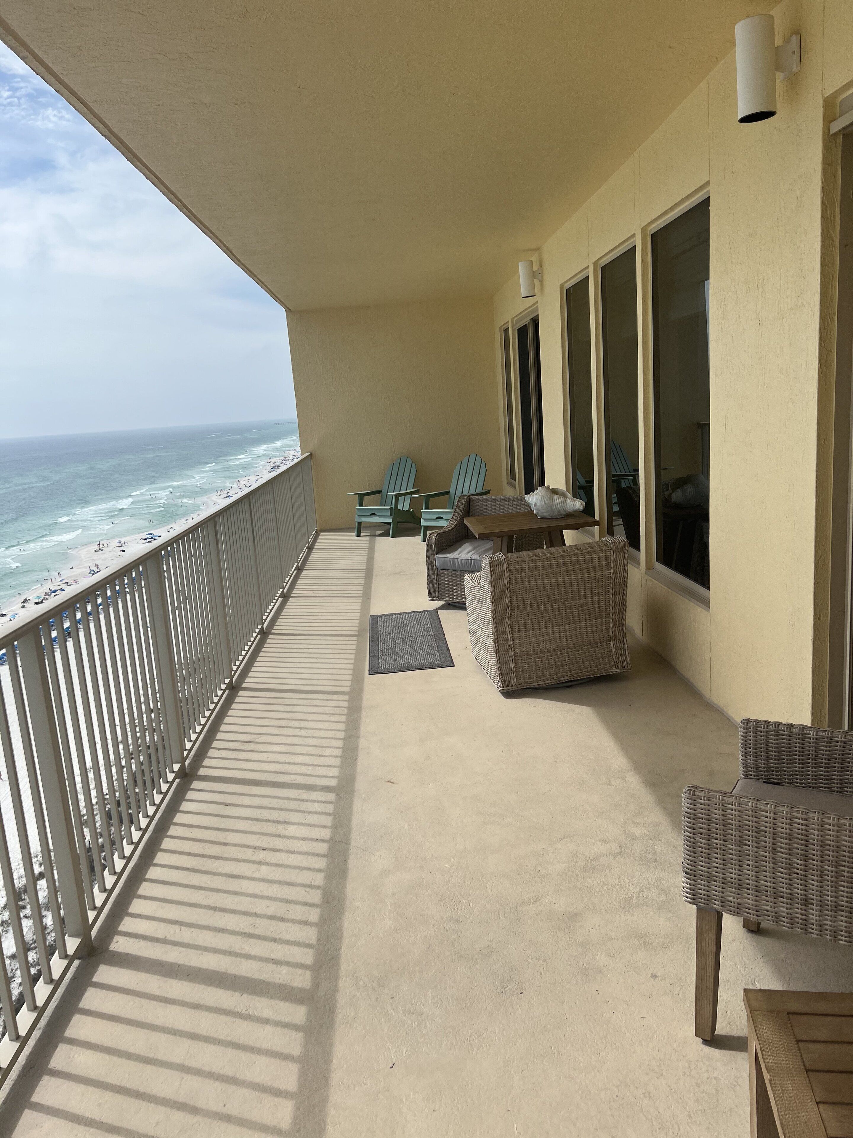 A balcony with wicker furniture, a view of the ocean, and a railing.