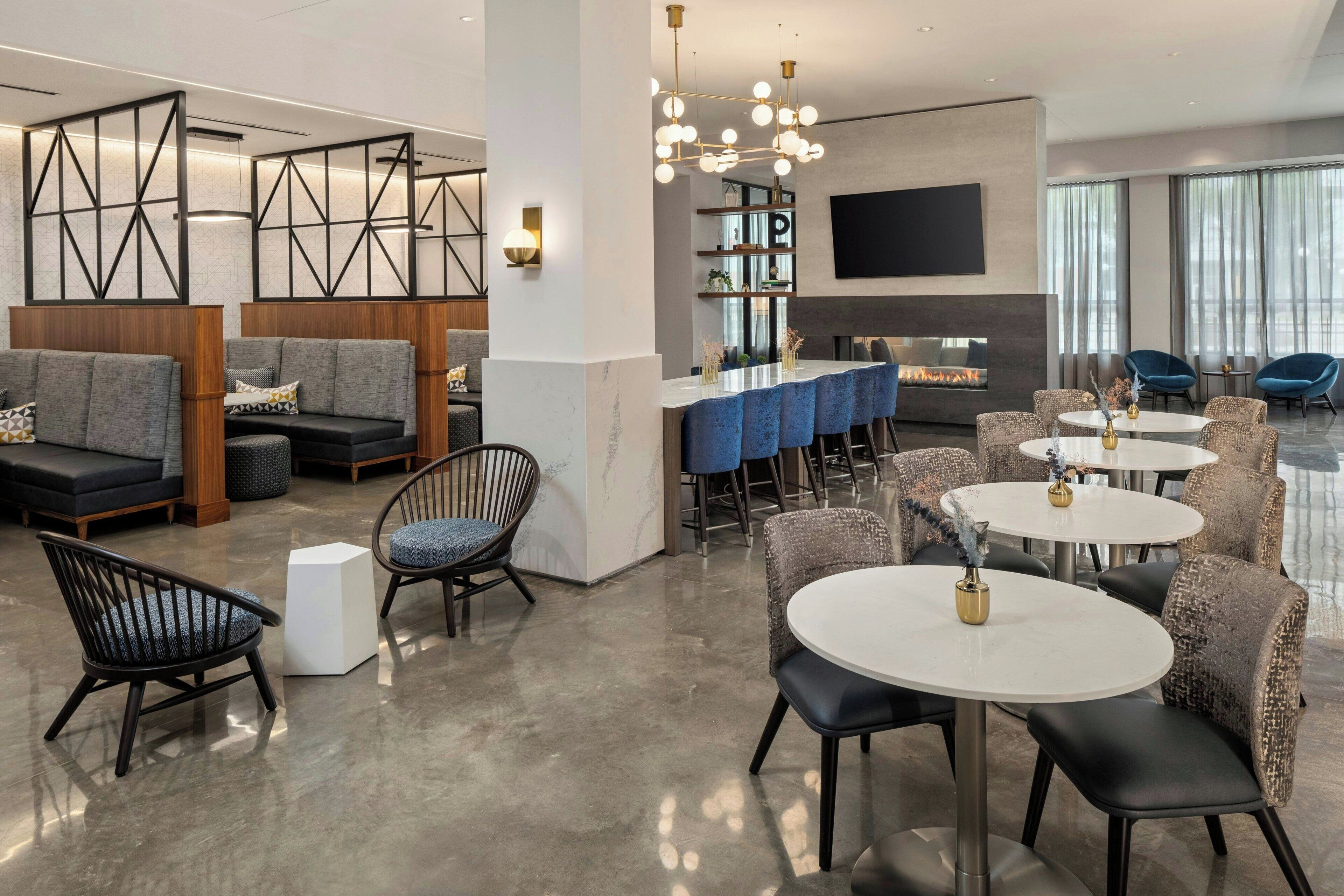 A modern hotel lobby with seating areas, a bar, and a fireplace.