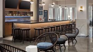 Een moderne bar met houten plafond, barstoelen en een toonbank met verschillende flessen en glazen.