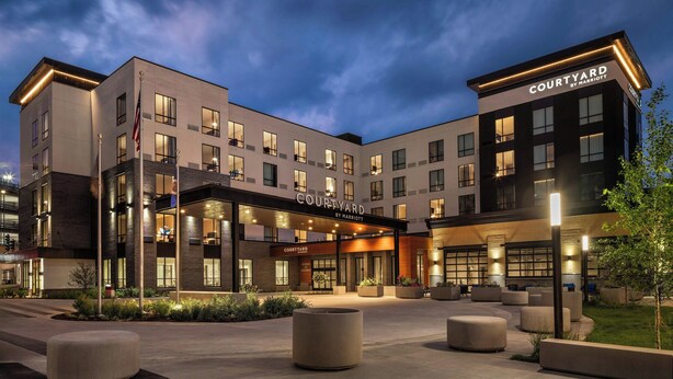 Een Courtyard by Marriott hotel met een modern design, een terras en een goed verlichte entree.