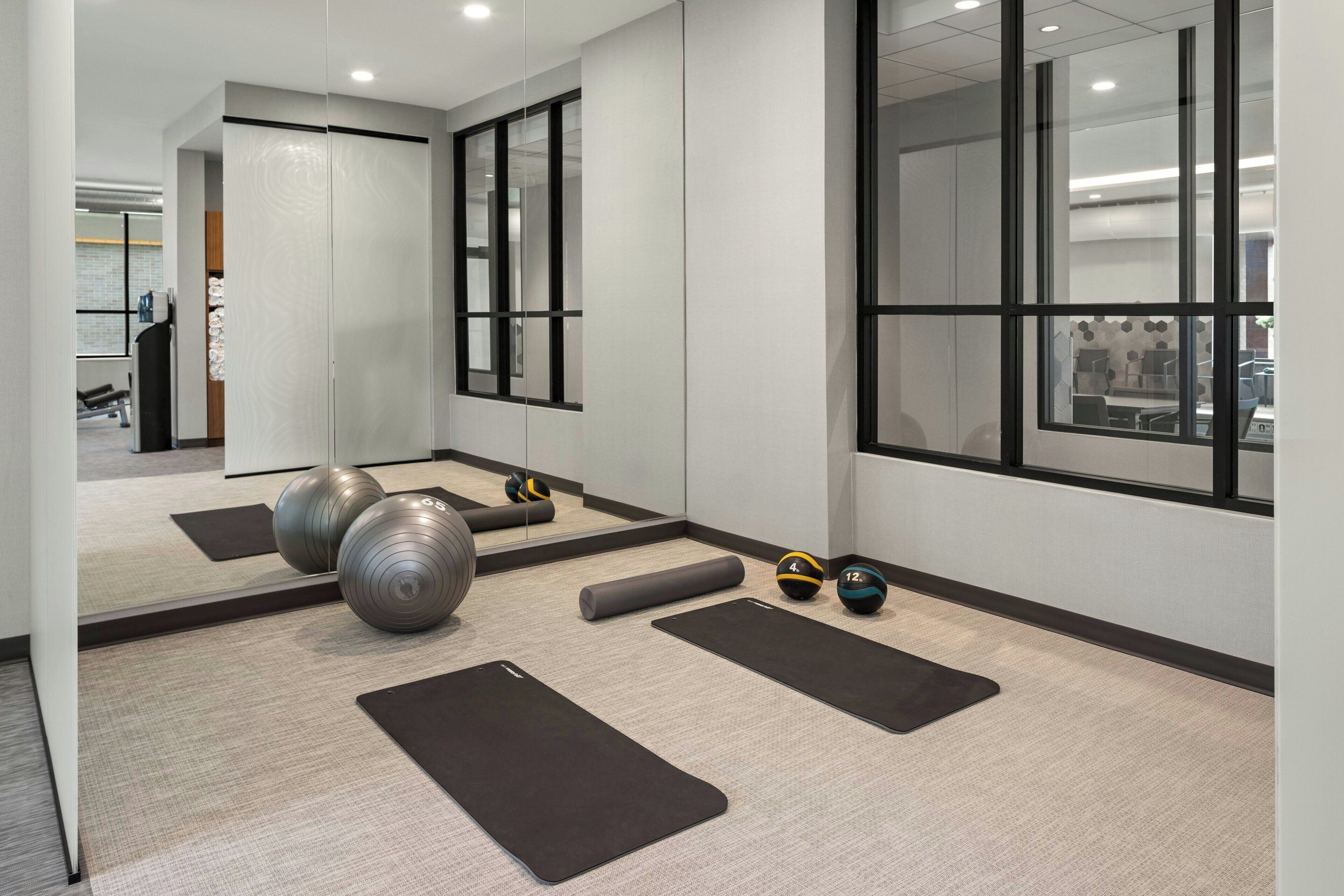 Un gimnasio con colchonetas, un espejo y pelotas de ejercicio.