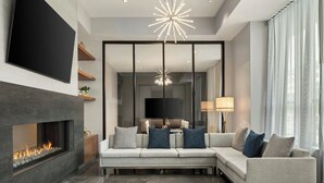 Een moderne woonkamer met een open haard, een grote flatscreen-tv, een bank en een kroonluchter.
