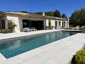 A modern outdoor pool area with a pergola, seating, and a clear view of the pool.