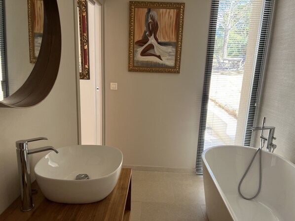 A bathroom with a white sink, a bathtub, and a large mirror.