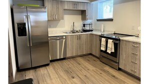 Une cuisine moderne dotée d’appareils électroménagers en acier inoxydable, de meubles en bois et d’une fenêtre laissant entrer la lumière naturelle.