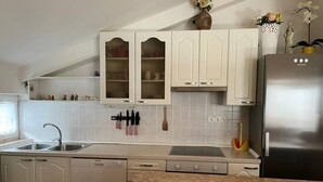 Une cuisine avec des armoires blanches, un réfrigérateur en acier inoxydable, un lave-vaisselle et un comptoir en granit.