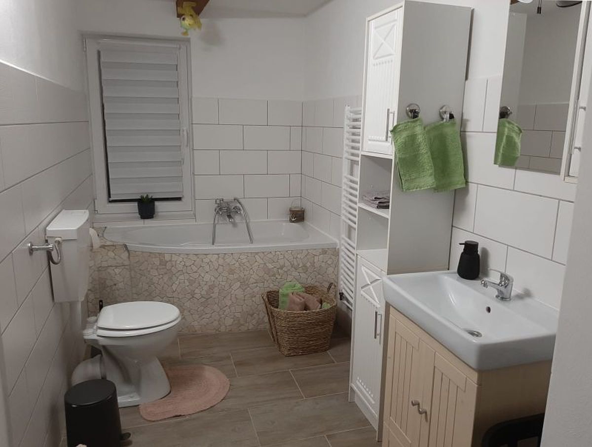 Kylpyhuone, jossa on wc, kylpyamme, pesuallas ja punottu kori.