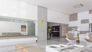 Un lobby moderno con una zona de estar, un mostrador de recepción y un separador de vidrio.